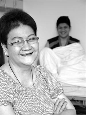Sau khi khối u tiêu biến, cô Du Jiani hoàn toàn tự tin quay trở về với cuộc sống bình thường, phía sau là ảnh của con trai - người đã hiến máu để cô điều trị miễn dịch sinh học