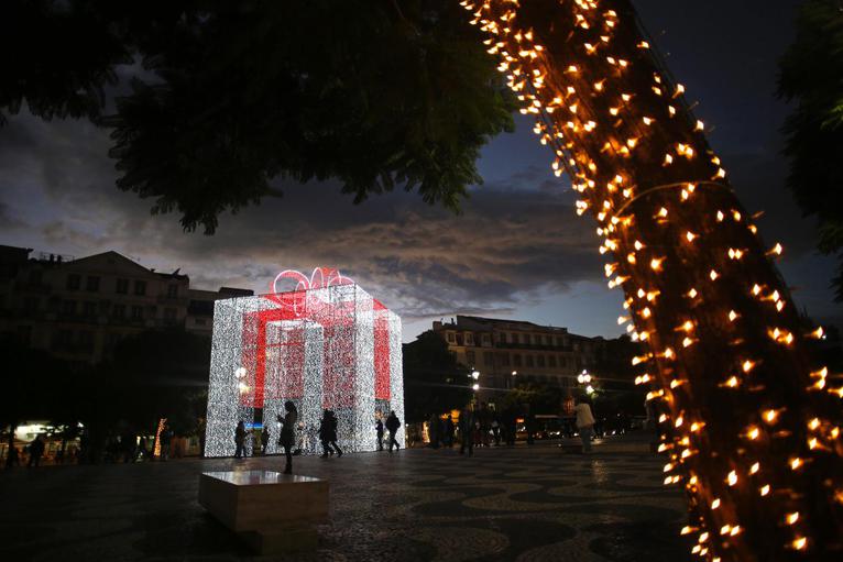 12. Người dân chụp ảnh lưu niệm bên cạnh hộp quà Giáng sinh tại Quảng trường Rossio Lisbon, Bồ Đào Nha ngày 14/12 (Ảnh: AP)